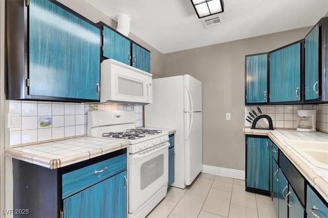 kitchen featuring light tile patterned flooring, decorative backsplash, tile countertops, and white appliances