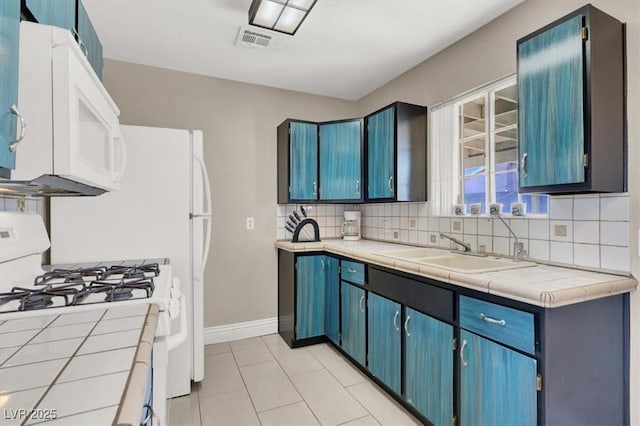 kitchen featuring white appliances, tile counters, decorative backsplash, sink, and light tile patterned floors