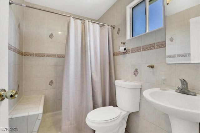 bathroom with toilet, a shower with curtain, tile walls, and sink