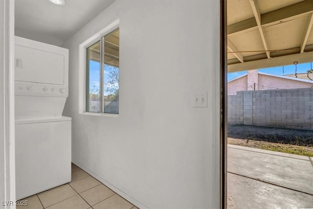 clothes washing area with light tile patterned floors and stacked washer and clothes dryer