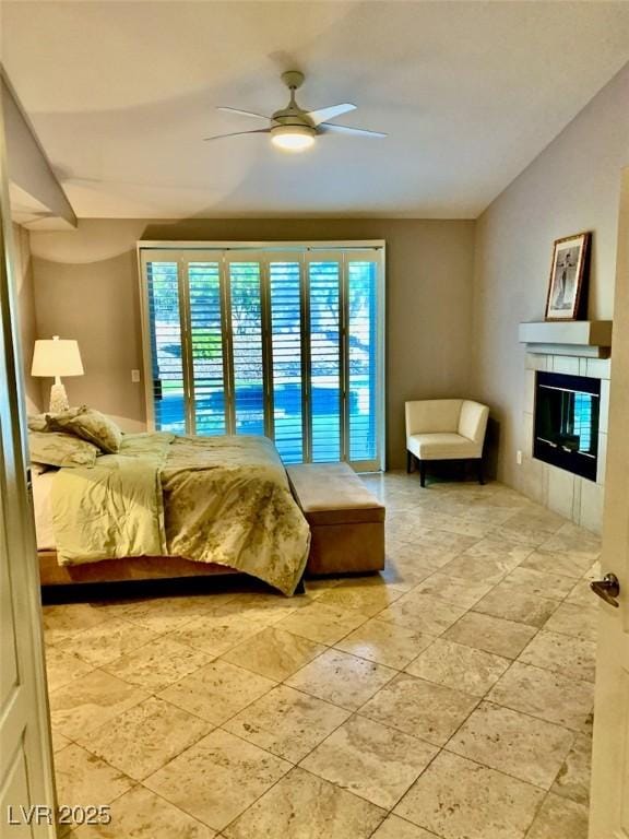 bedroom with ceiling fan, access to exterior, and a tiled fireplace