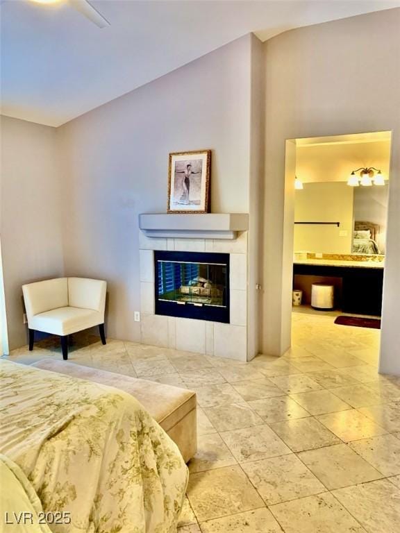 bedroom with ceiling fan, ensuite bath, and a tiled fireplace