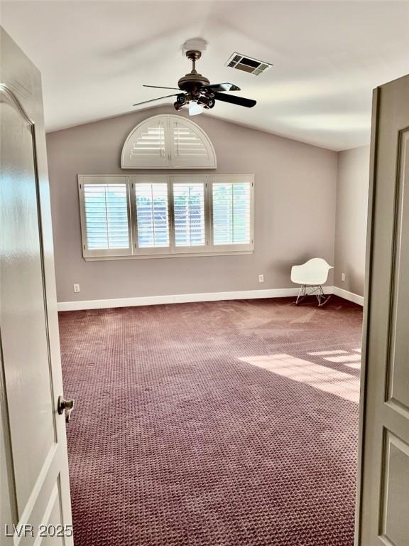 interior space with ceiling fan, dark carpet, and vaulted ceiling