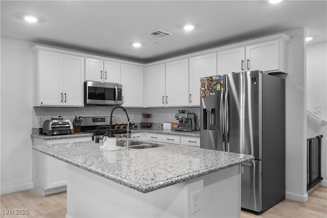 kitchen featuring light stone counters, white cabinetry, appliances with stainless steel finishes, and an island with sink