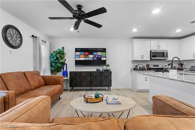 living room featuring ceiling fan and light hardwood / wood-style floors