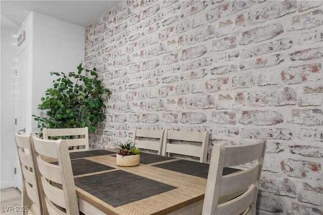 dining room featuring hardwood / wood-style flooring and brick wall