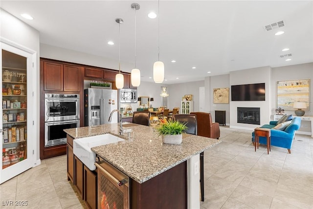 kitchen featuring a center island with sink, appliances with stainless steel finishes, sink, and pendant lighting