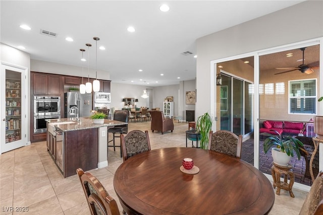 tiled dining area featuring ceiling fan and sink