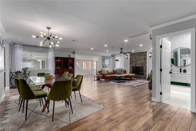 dining space with a fireplace, ceiling fan with notable chandelier, and crown molding