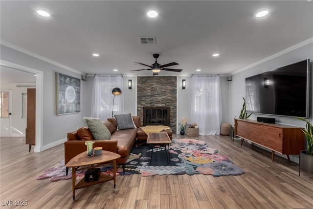 living room featuring a fireplace, crown molding, ceiling fan, and light wood-type flooring