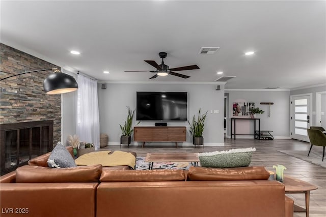 living room with a fireplace, a wealth of natural light, ornamental molding, and hardwood / wood-style floors