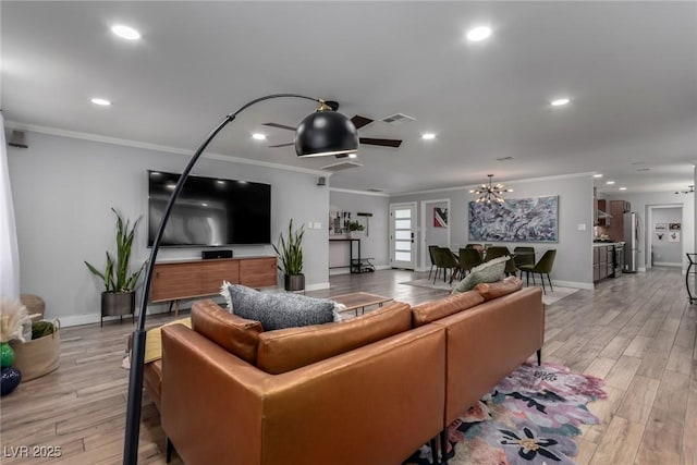 living room featuring light wood-type flooring, crown molding, and ceiling fan with notable chandelier