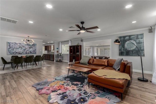 living room featuring crown molding, light hardwood / wood-style floors, and ceiling fan with notable chandelier