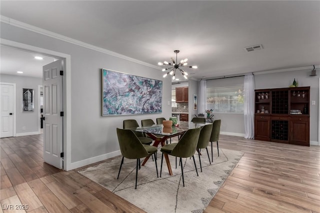 dining space with an inviting chandelier, crown molding, and light hardwood / wood-style floors