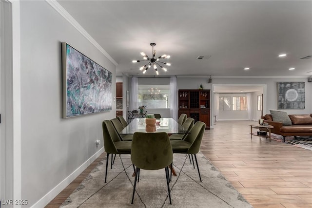 dining area featuring light wood-type flooring, ornamental molding, and an inviting chandelier