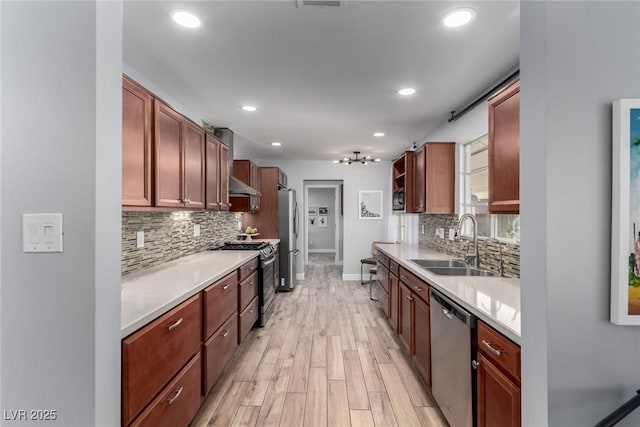 kitchen featuring stainless steel appliances, tasteful backsplash, sink, light hardwood / wood-style flooring, and range hood