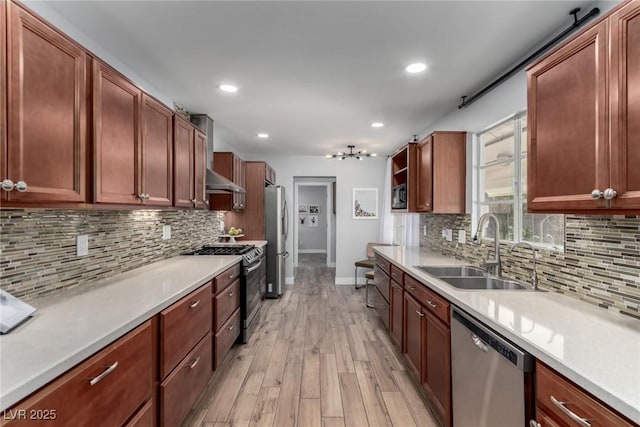 kitchen with decorative backsplash, appliances with stainless steel finishes, sink, and light hardwood / wood-style floors