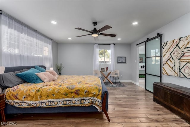 bedroom featuring ceiling fan, hardwood / wood-style floors, and a barn door