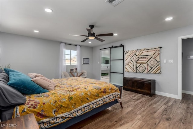 bedroom featuring ceiling fan, hardwood / wood-style flooring, and a barn door