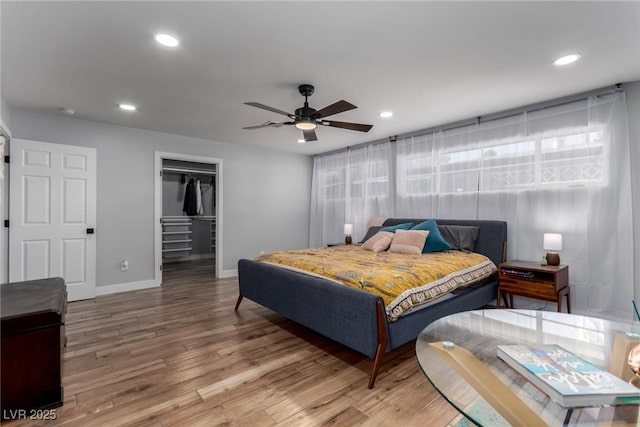 bedroom featuring a spacious closet, hardwood / wood-style flooring, a closet, and ceiling fan