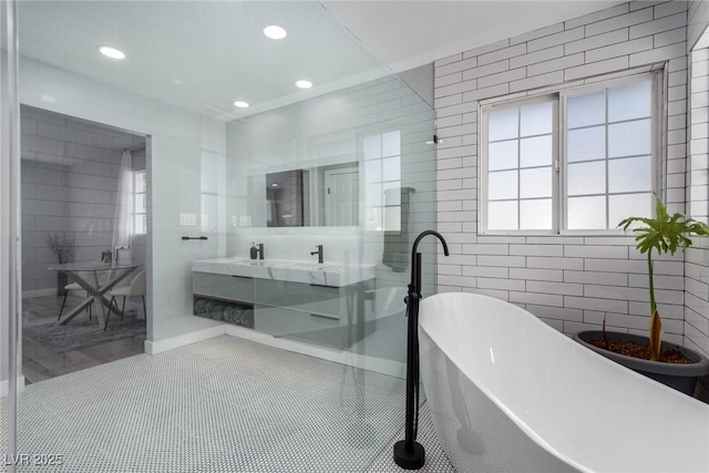 bathroom featuring vanity, tile walls, tile patterned floors, and a bath