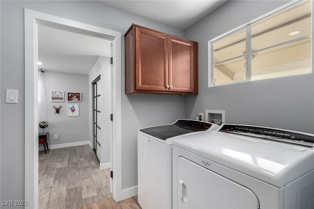 laundry room featuring light hardwood / wood-style flooring, washing machine and clothes dryer, and cabinets