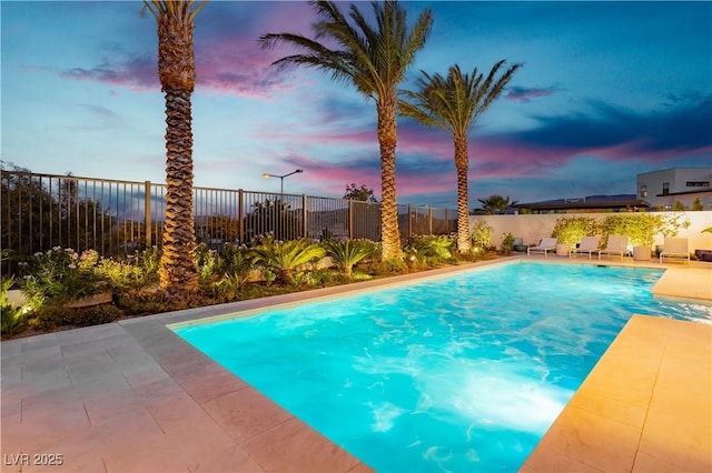 pool at dusk with a patio area