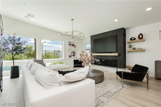 living room with wood-type flooring, a large fireplace, and an inviting chandelier