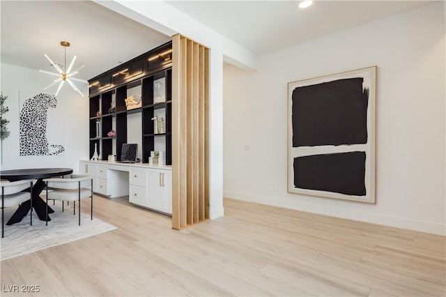 home office featuring light wood-type flooring and a notable chandelier