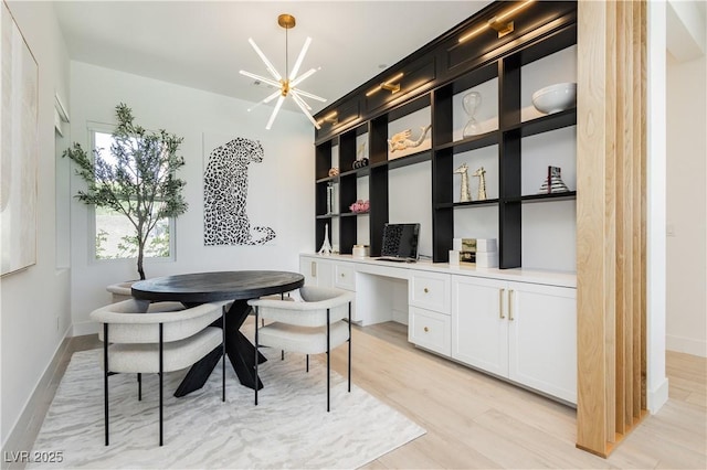 home office with a chandelier, built in desk, and light wood-type flooring