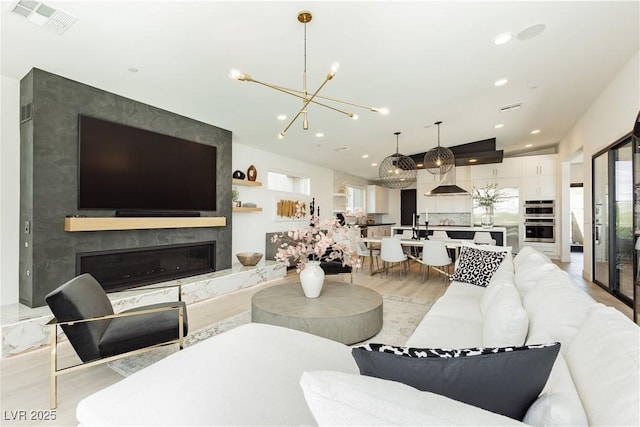 living room featuring light hardwood / wood-style floors, lofted ceiling, an inviting chandelier, and a fireplace