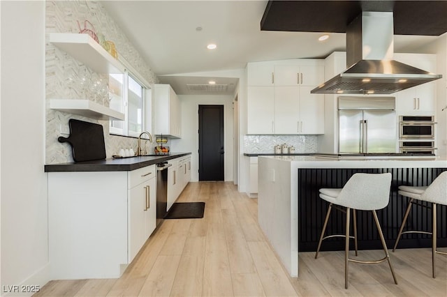 kitchen with white cabinetry, light hardwood / wood-style floors, island exhaust hood, stainless steel appliances, and sink