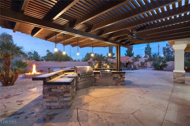 patio terrace at dusk with an outdoor fire pit, area for grilling, and a pergola