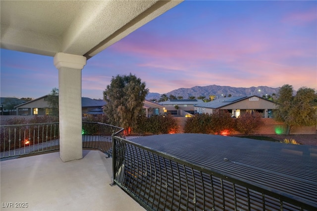 patio terrace at dusk featuring a mountain view and a balcony