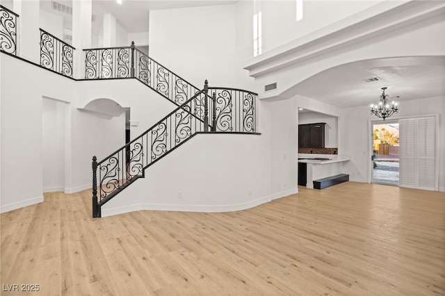 living room featuring a chandelier, a towering ceiling, and light hardwood / wood-style flooring