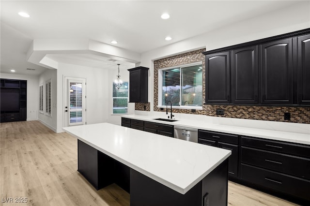 kitchen featuring a kitchen island, stainless steel dishwasher, decorative backsplash, sink, and hanging light fixtures