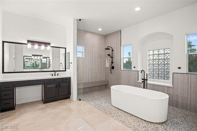 bathroom with tile walls, separate shower and tub, and vanity