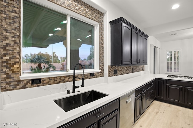 kitchen with light stone countertops, stainless steel appliances, light hardwood / wood-style floors, and sink