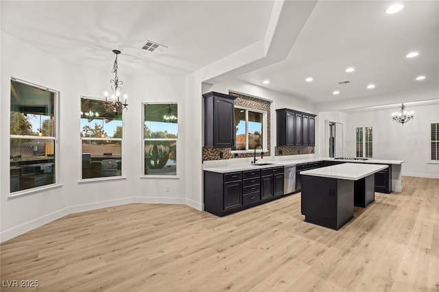 kitchen featuring a center island, decorative light fixtures, decorative backsplash, sink, and light hardwood / wood-style flooring