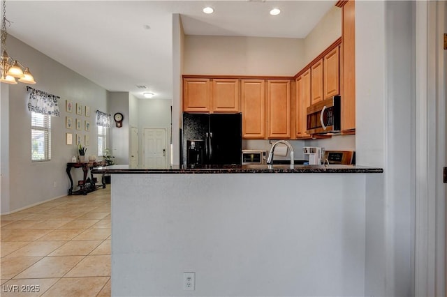 kitchen featuring black fridge, light tile patterned floors, dark stone countertops, and kitchen peninsula