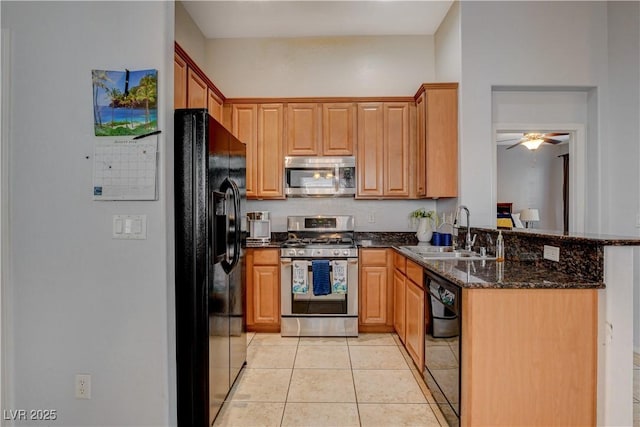 kitchen with ceiling fan, light tile patterned flooring, dark stone counters, black appliances, and sink