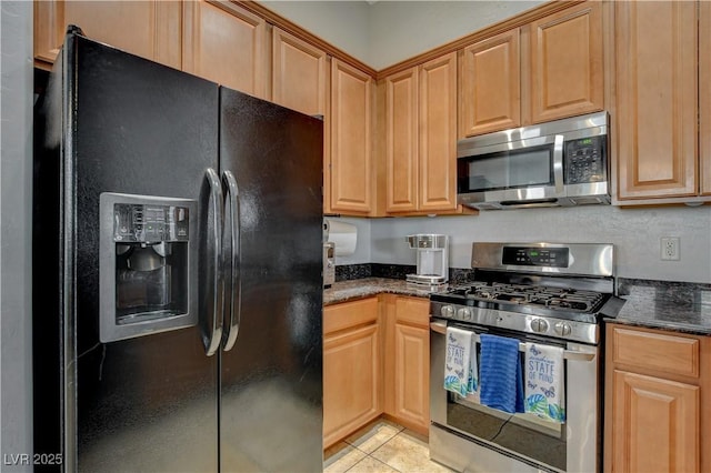 kitchen with light tile patterned floors, stainless steel appliances, and dark stone counters