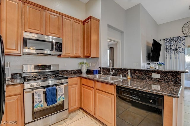 kitchen featuring stainless steel appliances, dark stone countertops, sink, kitchen peninsula, and light tile patterned flooring