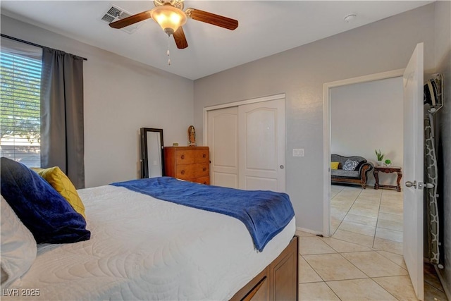 tiled bedroom with ceiling fan and a closet