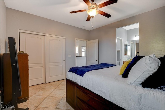 bedroom with ceiling fan, connected bathroom, light tile patterned floors, and a closet