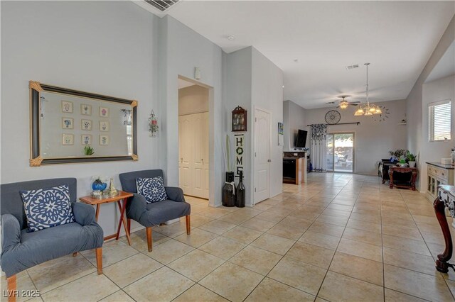 tiled living room featuring ceiling fan with notable chandelier