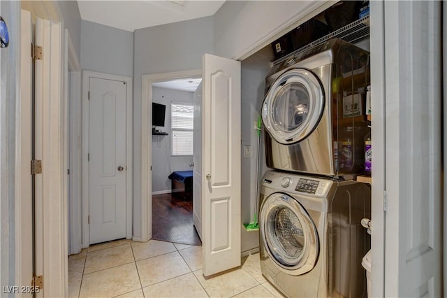 washroom featuring stacked washer and dryer and light tile patterned flooring