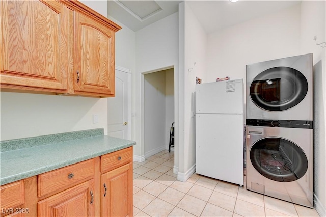 clothes washing area with cabinets, light tile patterned floors, and stacked washer and clothes dryer