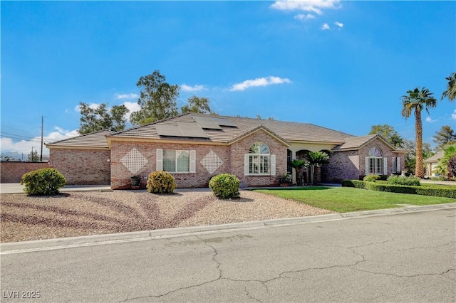 ranch-style home featuring a front lawn and solar panels