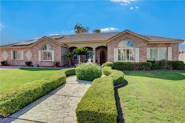 single story home with a front yard and solar panels